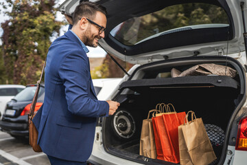 businessman put shopping bags in the car trunk on the parking lot