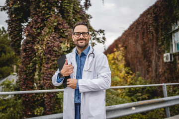 Portrait of adult man doctor stand with clipboard on the terrace