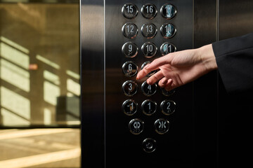 A businessman confidently stands in an elevator while pressing a button to reach his desired floor