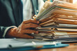 © MVProductions - Businessman hands searching information in Stack of papers files on work in office, business report paper or piles of unfinished documents achieves with clips on offices Business concept