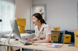 © PaeGAG - Young woman entrepreneur is sitting at her desk and looking excitedly at her computer screen, happy about her small business' online sales