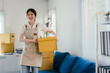 © PaeGAG - Young asian woman who owns a small business is smiling happily as she is packing products into parcels for delivery, working from home