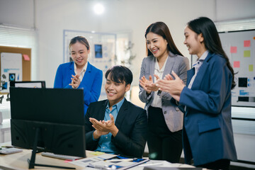 Poster - Team of happy asian businesspeople are standing in the office, looking at a computer screen and applauding after a successful online meeting