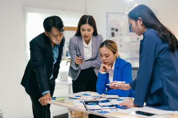 Poster - Asian business team analyzing data charts in office, brainstorming solutions with laptops, showing teamwork and collaboration