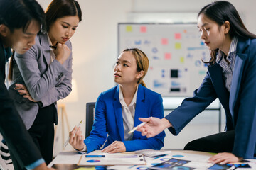 Fototapete - Team of asian businesspeople are discussing a project, analyzing financial documents with charts and graphs using pens to point at the information