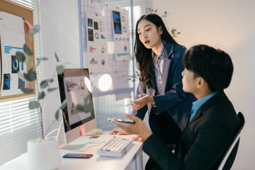 Two professionals in a bright office collaborate on charts and data, discussing finance and marketing strategies for their startup