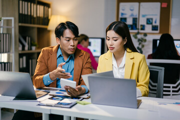 Poster - Two business partners analyzing financial data in a busy office, using a calculator and laptop, focusing on a project together