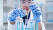 © Supapich - Woman research scientist biology chemistry medicine pouring liquid from beaker to test tube indoor science laboratory room, adult female person blue glove work discovery experiment medical chemist