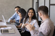 © fizkes - Happy young Indian employee woman talking to male colleagues at coworker workplace, laughing, smiling, sitting at workplace. Diverse co-workers discussing teamwork, networking