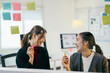 © Parichat - Two asian businesswomen are brainstorming and discussing about a new project, writing ideas with a marker on a glass board in the office
