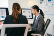 © Parichat - Two asian businesswomen are working together in the office. They are looking at charts and graphs on a computer screen, analyzing financial data