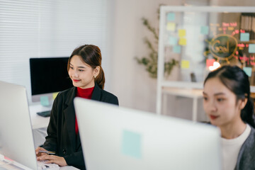 Two young businesswomen work diligently on laptops in a modern office, showing focus and teamwork. Professionalism and dedication shine as they use technology to drive their startup forward