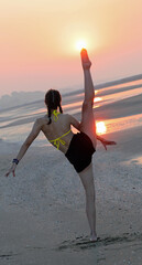 girl performing dynamic gymnastic exercises facing the sun kicking her leg high into the air