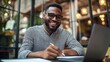 © ORG - A young man smiles brightly as he sits and fills out passport documents. or visa at an important stage Work with laptop placed on table