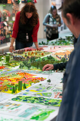 Fototapete - Urban planners sketching eco-friendly city layouts, solar panels, and green roofs, vibrant concept boards displayed