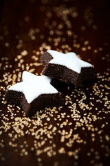 Christmas cookies (cinnamon stars) and brown sugar on dark background. Close up.