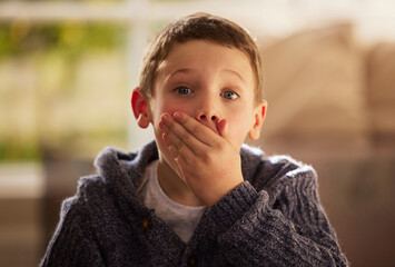 Portrait, surprise and boy cover mouth, home and emotions with emoji in living room. Face, childhood and kid in lounge, announcement and shocked with reaction, wow and omg with facial expression