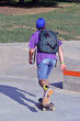 © Gustavo Andrade - Skate boarding boy wearing a bag skating on skate board outdoors park.