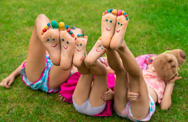 Poster - Children's feet painted on the grass. Selective focus.