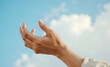 © Marina - Hand reaching towards the sky with clouds in a blue background representing freedom and hope