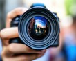 © melhak - Close up of a person holding a camera with a reflection of a building in the lens - Concepts