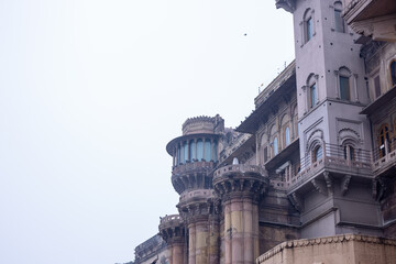 adesh, India - January 19 2024: Architecture of ancient building, Historic Varanasi city with ancient temples and building architecture at assi ghat along with wooden boat in river.