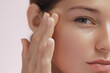 © Buyanskyy Production - Extreme close-up of a woman s face with clear skin, touching her temple, highlighting facial features and skincare. The soft focus and natural lighting highlight her beauty and serene expression.
