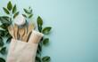 © Georgii - Eco-friendly tableware concept with a white paper bag filled with wooden cutlery surrounded by green leaves and a compostable cup on a light green background