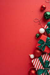 stylish vertical christmas presents with green ribbons and decorative ornaments on a vibrant red bac