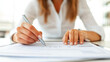 © JVLMediaUHD - A Person Writing Notes on a Document With a Pen While Seated at a Modern Desk in a Bright Office Environment During the Day