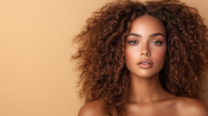 a mesmerizing woman with voluminous curly hair and glowing skin stands poised against a soft beige b
