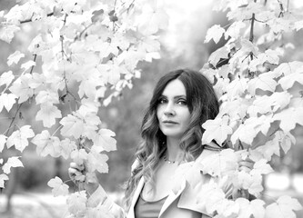 Black and white photo of a girl in a light raincoat walking in an autumn city. A walk in nature, relaxation. Seasonality concept