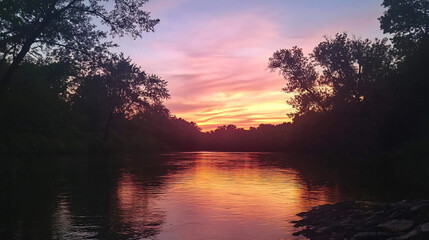 Wall Mural - A sunset view over a calm river, with silhouettes of trees against the colorful sky.