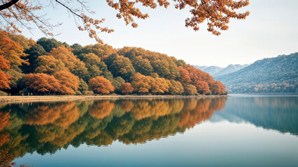 A scenic autumn landscape with a lake surrounded by colorful trees reflecting in the calm water. The trees have vibrant orange, red, and yellow foliage, creating a beautiful and serene natural scene