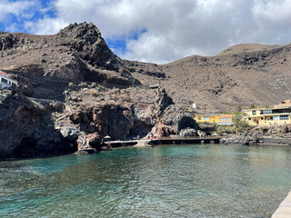 Rocky cove with turquoise water and houses on the cliff