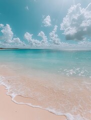 Wall Mural - A clear blue sky with puffy white clouds above a pristine sandy beach with crystal clear turquoise water gently lapping the shore.