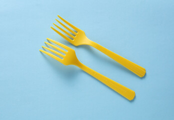 Yellow Plastic forks on blue background. Top view