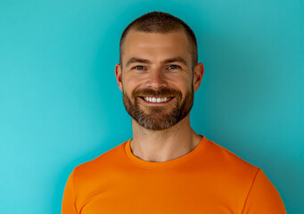 Man with short hair and a beard, wearing an orange T-shirt, in a front view on a light blue background.