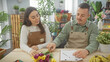 © Krakenimages.com - Man and woman in aprons arranging flowers at a flower shop counter, with plants and florist tools in the background.