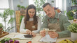 © Krakenimages.com - A woman and a man in aprons examine czech crowns in a florist shop full of green plants.