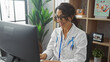 © Krakenimages.com - A mature woman doctor with glasses smiling while working at a computer in a clinic office setting