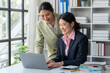 © Wicitr - Collaborative Success: Two smiling Asian businesswomen review data on a laptop, showcasing teamwork and professional growth in a modern office setting.