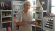 © Krakenimages.com - Woman holding tablet in home decor store with various decorative items in the background, wearing apron in indoor cozy setting giving warm ambiance