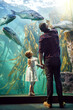 © C.Arcurs/peopleimages.com - Back, dad and girl with fish in aquarium for education experience, marine learning and environment study. Family, glass and watching tank with sea animals, ecology development and bonding together