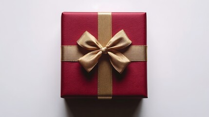 Wall Mural - Close-up of a red gift box with a gold ribbon bow, shot from above on a white background