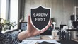 © Natalia - A person holding a shield with the words 'Safety First', emphasizing the importance of safety in the workplace environment.