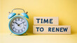 © deimos.az - Time to renew, text in a gold frame on a pink background, near an alarm clock. Business, strategies, plans, and goals concepts.