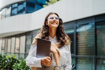 Young businesswoman going to work in front of modern business building