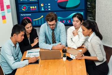 Diverse group of business analyst team analyzing financial data report. Finance data analysis chart and graph dashboard show on TV screen in meeting room for strategic marketing planning. Meticulous