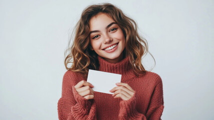 Young woman in cozy sweater holding blank card in studio setting